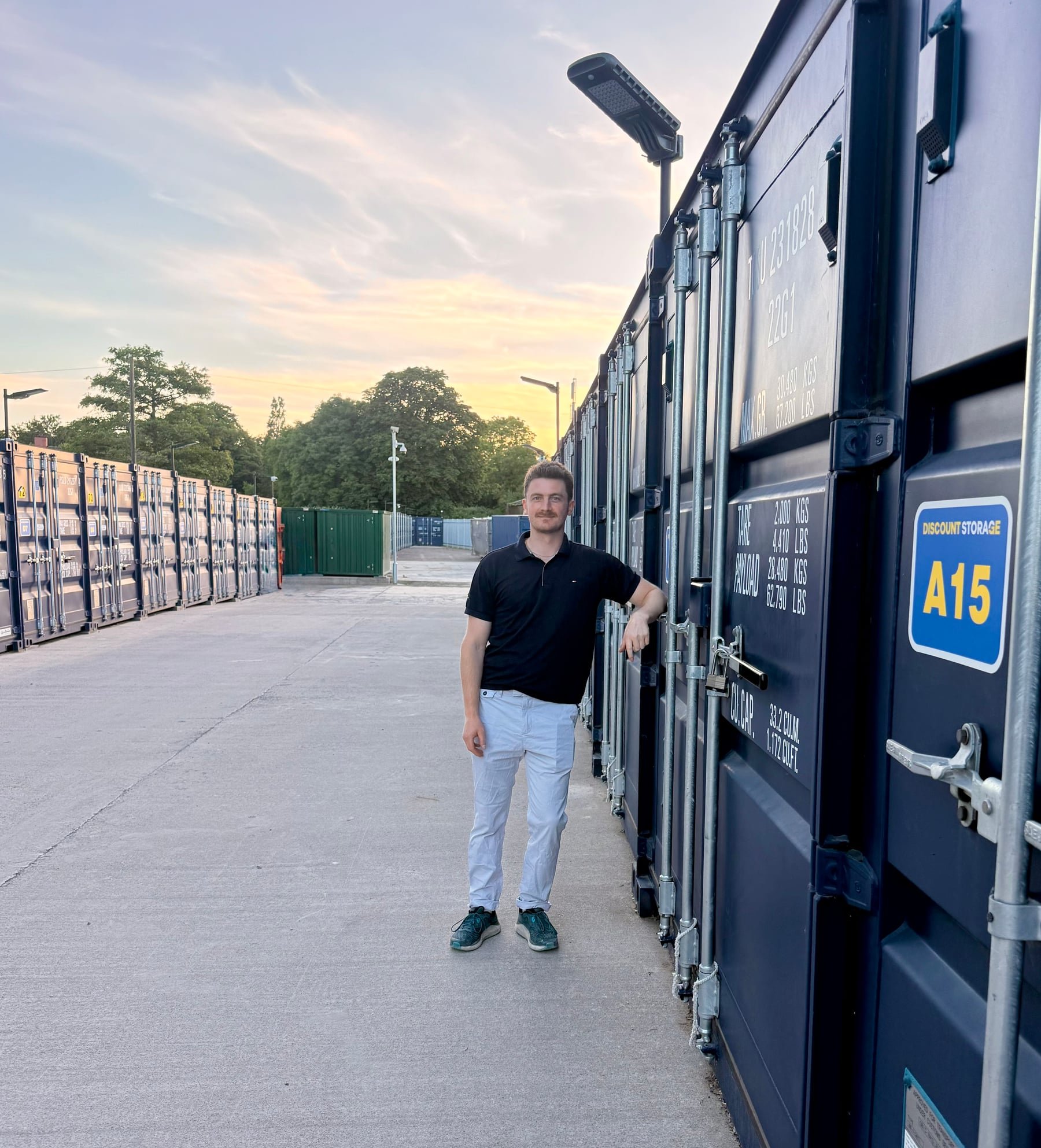 One of the Discount Storage founders standing beside a row of blue storage containers at the Henbury, Bristol site