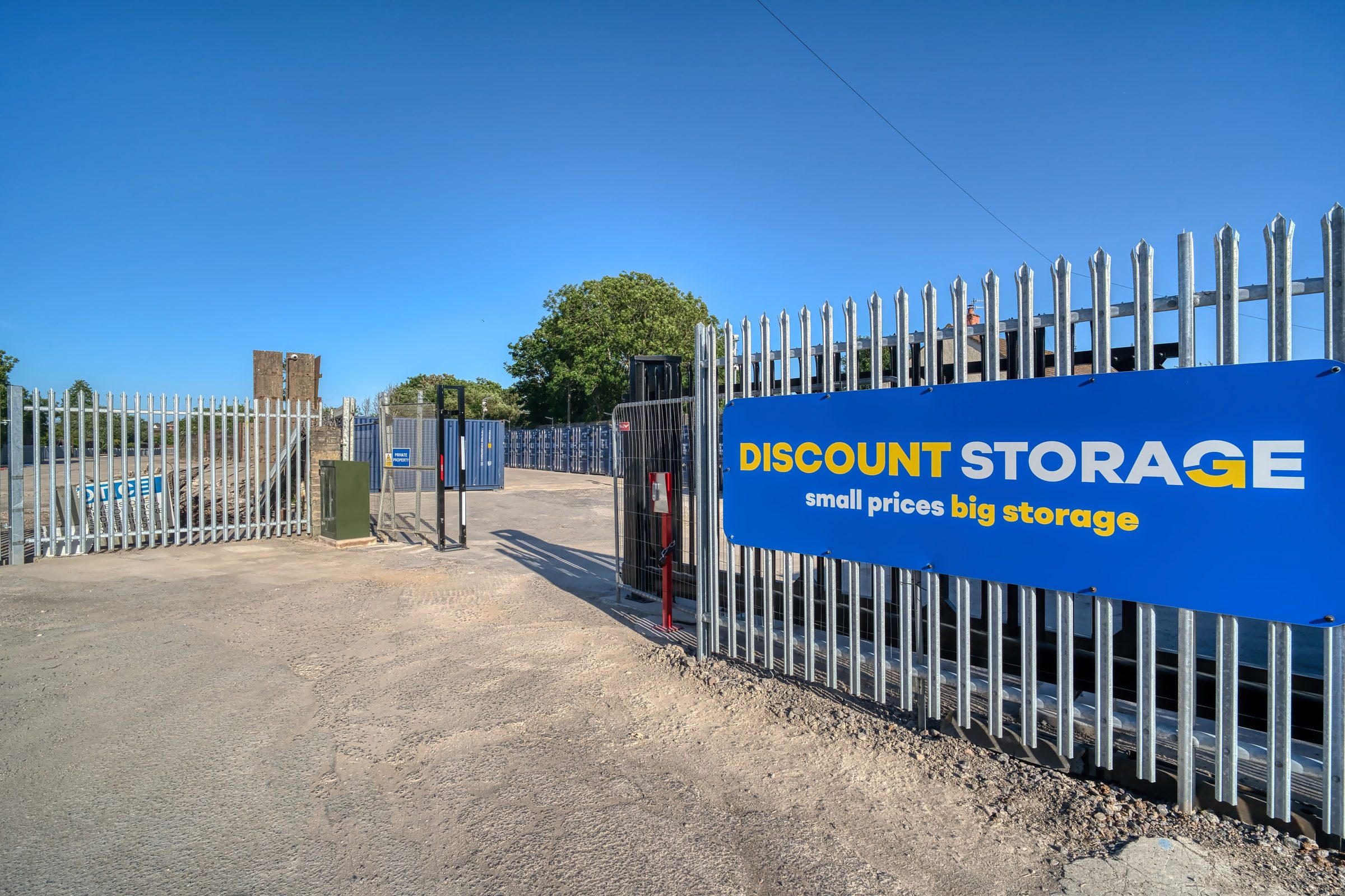 Palisade security gate standing open at the yard entrance, wide enough for vans and trailers